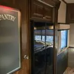 view of kitchen. Pantry with lighted sign and double door refrigerator
