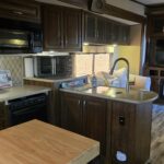 view of kitchen with sink and airfryer in the background. cutting board island in the middle