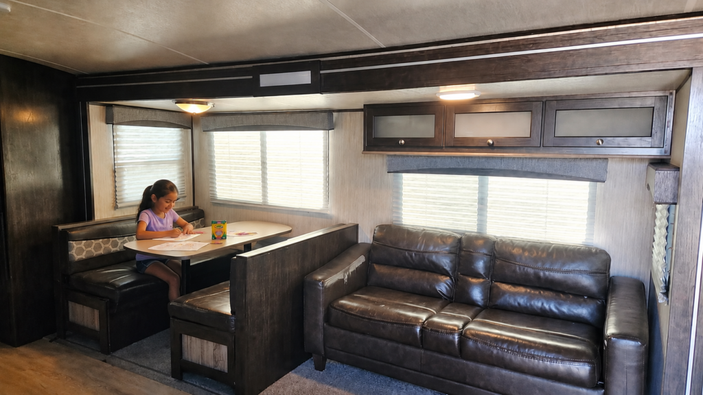 Family RV Rental Near Garner State Park Child coloring at the dinette inside a family-friendly RV rental at Pitmaster RV Park in Concan, Texas.