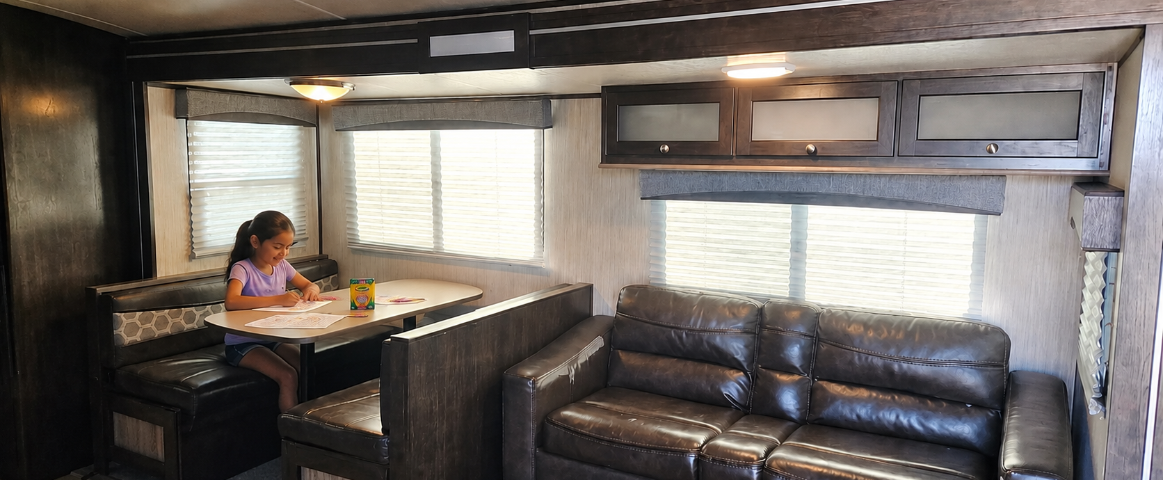 Child coloring at the dinette inside a family-friendly RV rental at Pitmaster RV Park in Concan, Texas.