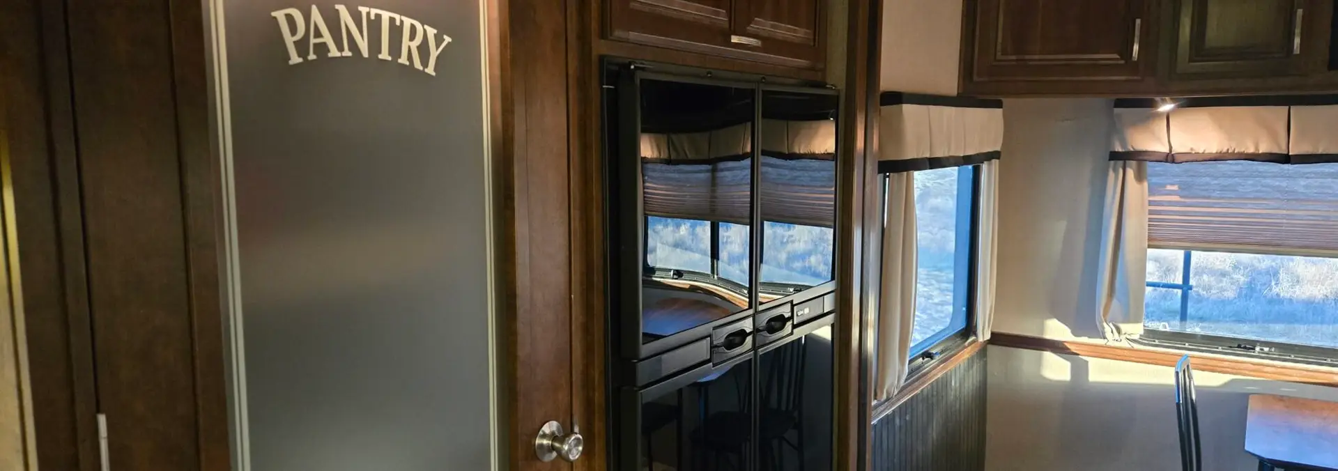Luxury RV rental interior with full kitchen, pantry, dining area, and modern amenities at Pitmaster RV Park in Concan, Texas.