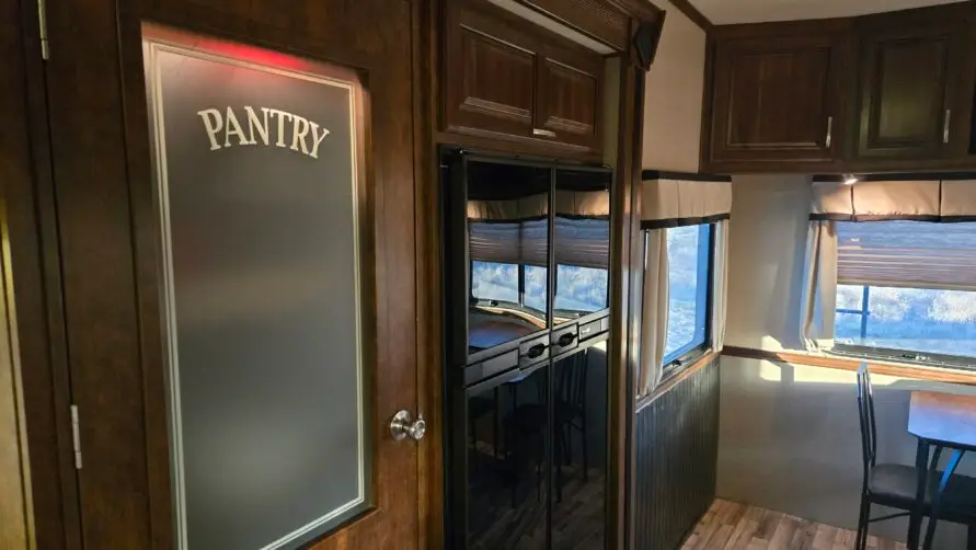 Luxury RV rental interior with full kitchen, pantry, dining area, and modern amenities at Pitmaster RV Park in Concan, Texas.