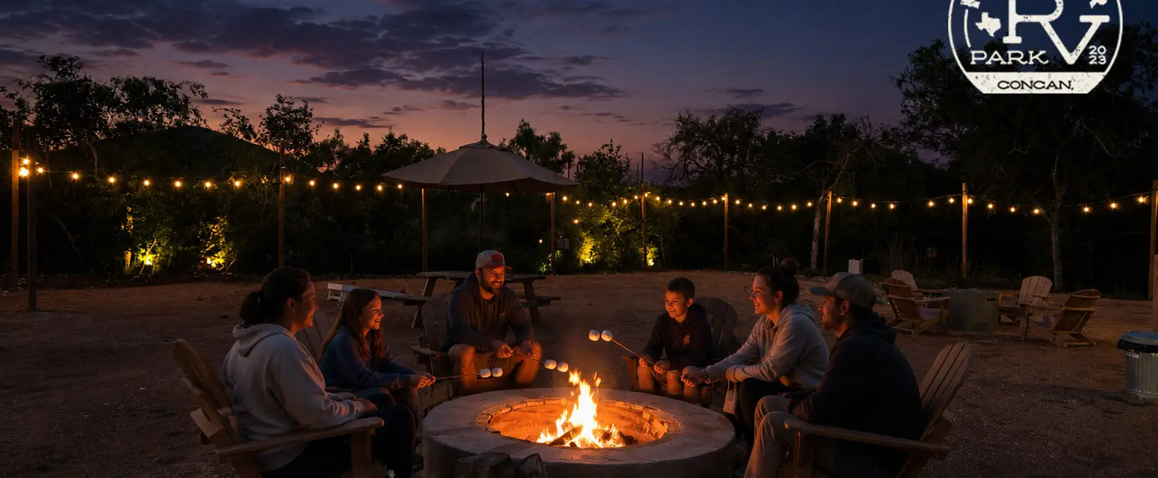 Families roasting marshmallows around a campfire at Pitmaster RV Park in Concan, Texas under the Texas Hill Country night sky.