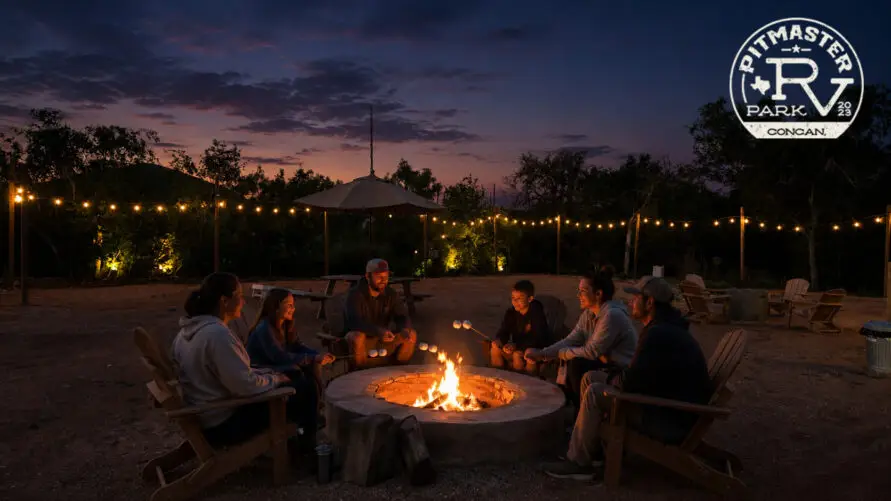 Families roasting marshmallows around a campfire at Pitmaster RV Park in Concan, Texas under the Texas Hill Country night sky.