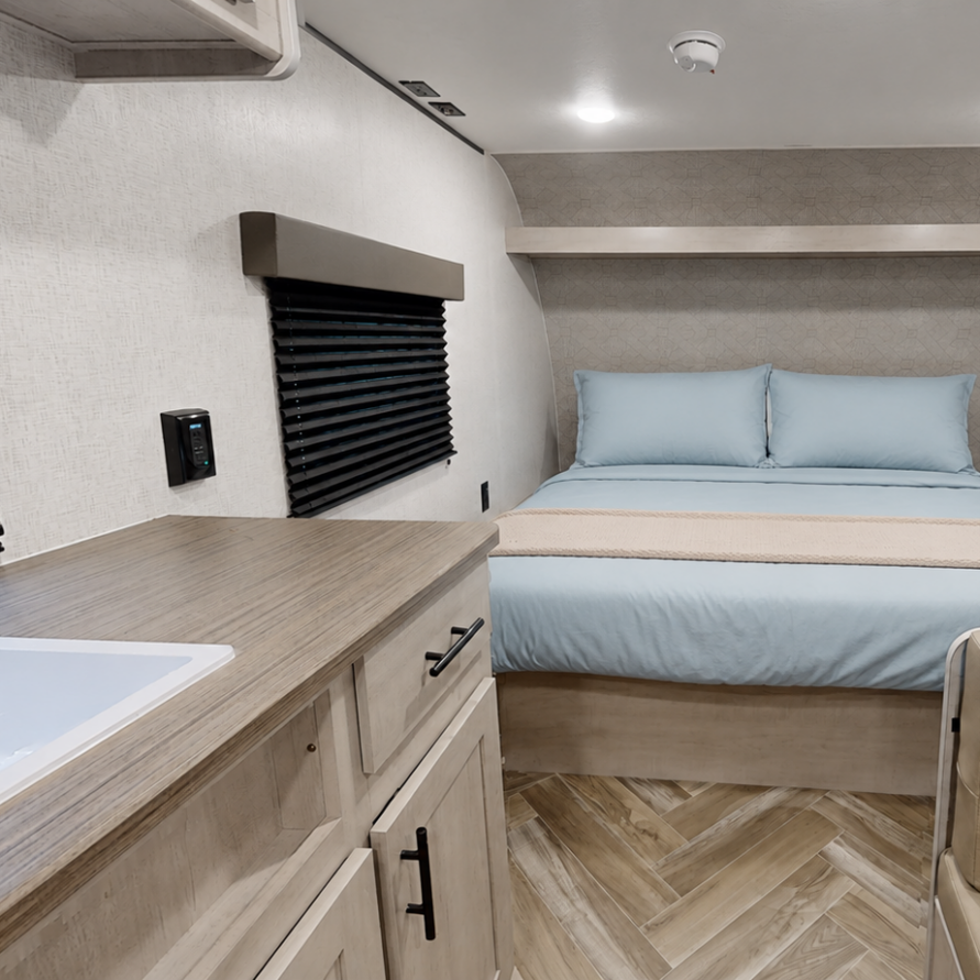 Interior of a cozy RV rental with queen bed, kitchenette, and private bathroom at Pitmaster RV Park near Garner State Park in Concan, Texas.