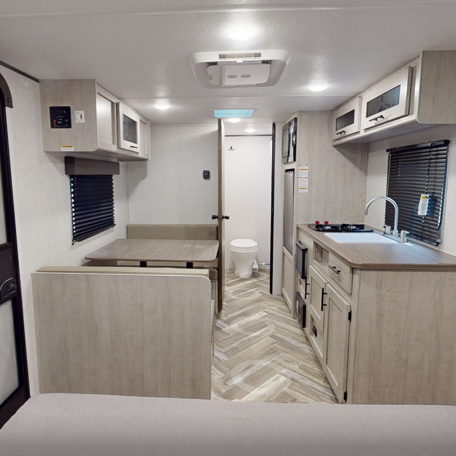 Modern RV rental interior with kitchenette, dining area, and private bathroom at Pitmaster RV Park near Garner State Park in Concan, Texas.